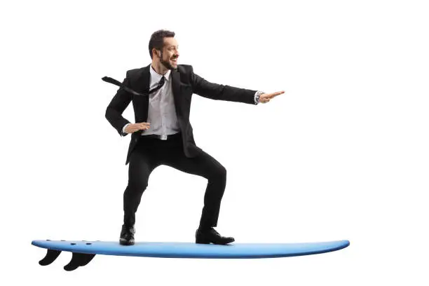 Full length profile shot of a businessman riding a surfboard isolated on white background