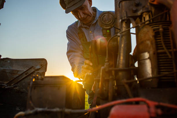 Mature Men operating a tractor on a farm during sunset