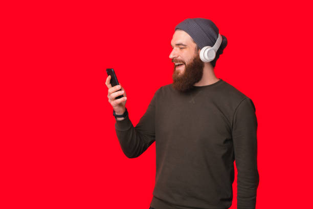 Young excited bearded man is in love with the music, headphones and phone he is holding. stock photo