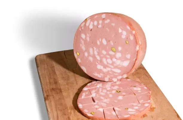 Mortadella Bologna with pistachios on wooden cutting board isolated on white