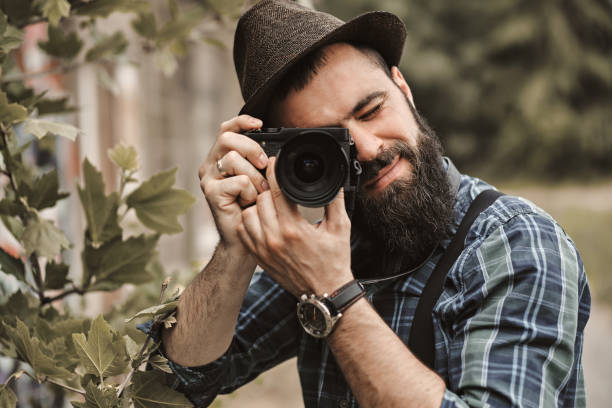 istock A handsome young man with a beard is taking photos in a green park. 1314961842