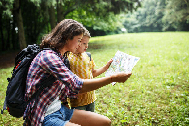 istock Mother and her little sons hiking .They taking a break and examining map. 1314962434