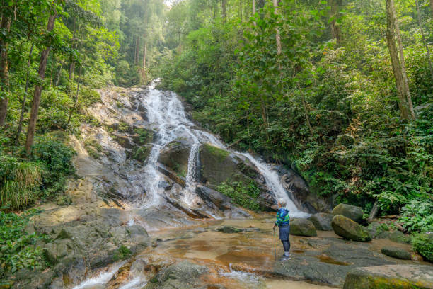 istock Senior woman stands in front of refreshing waterfall 1314963564