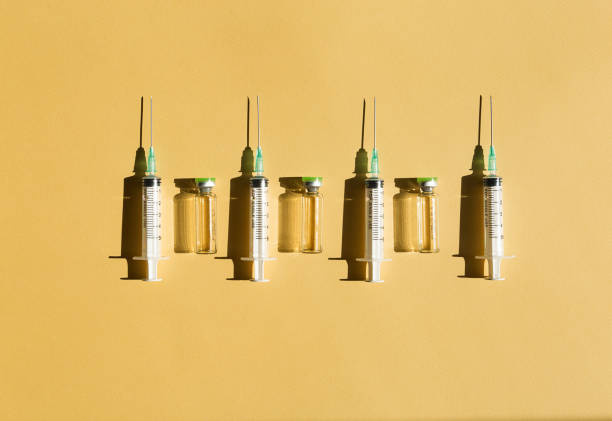 syringes and injection bottles lie in a row on a yellow background - syringe vaccination vial insulin imagens e fotografias de stock