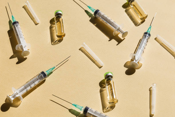 istock Syringe and Vaccine against yellow background 1314966999