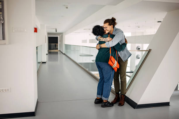 Excited colleague hugging each other in office hallway