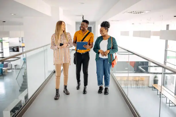 Young trainees walking in office hallway and discussing ideas