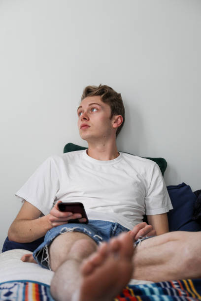 istock Young man contemplating while laying on his bed using his phone 1314972126
