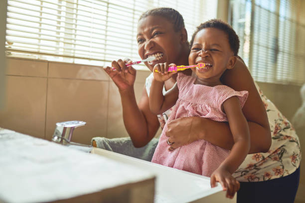 schuss einer frau und ihrer tochter, die sich zu hause die zähne putzen - tooth character stock-fotos und bilder