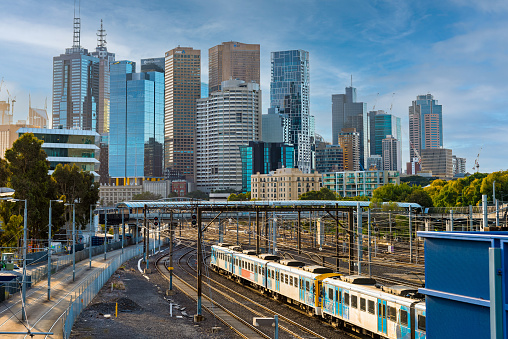 Melbourne, Victoria, Australia, April 17th, 2021: The many high rise buildings of the Melbourne downtown with a Metro train in the foreground in the late afternoon light