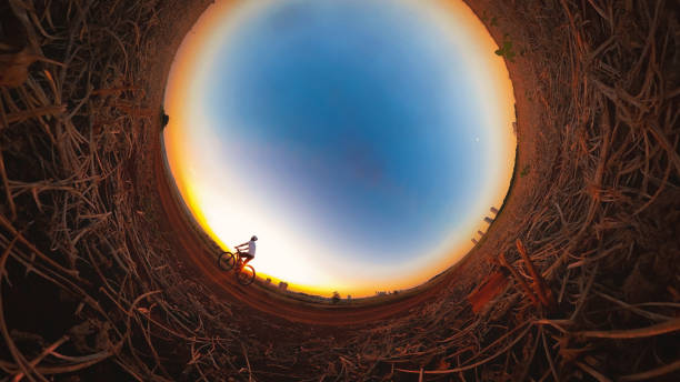 Black man with helmet and glasses riding a bicycle at sunset