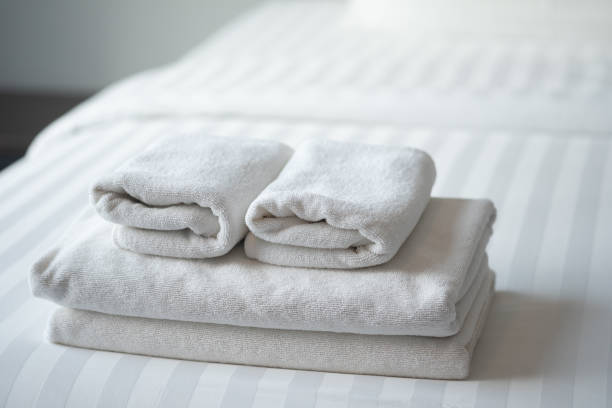 Folded white towels on the hotel bed, feels cozy Folded white towels on the hotel bed, feels cozy linen stock pictures, royalty-free photos & images