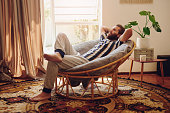 Shot of a young man relaxing on a chair at home