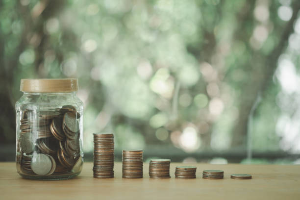 istock Thai coins (baht) in a clear glass jar with money stack step up growing growth saving money 1314981692