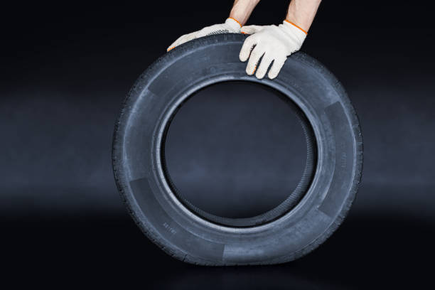 istock Man presses on new tire on creative black background. Tire changing concept 1314985767