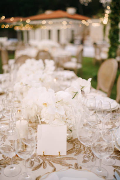 istock Empty card stands on a table covered with a white tablecloth against the background of a bouquet of flowers and empty glasses 1314986106