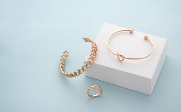 Modern golden bracelets and ring on white and blue background with copy space