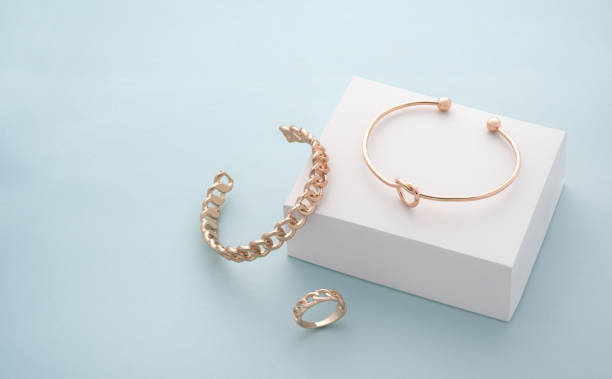 Modern golden bracelets and ring on white and blue background with copy space Modern golden bracelets and ring on white and blue background jewelry stock pictures, royalty-free photos & images
