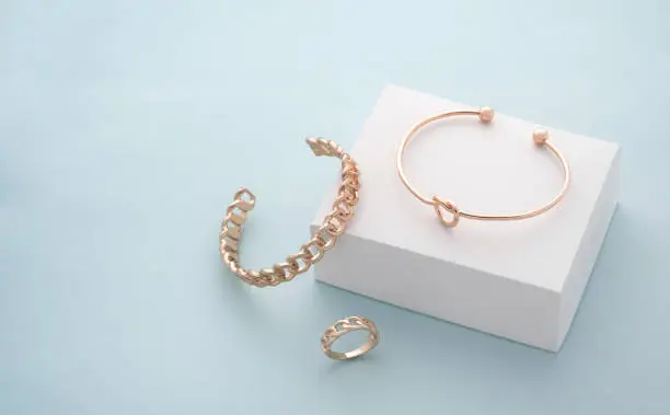 Modern golden bracelets and ring on white and blue background