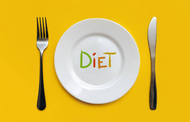 istock A white plate on which the word Diet is written standing on a yellow tablecloth . The concept of a balanced diet, ration and medical fasting. Top view, white background, copy space. 1314990004