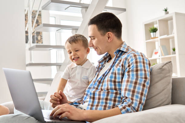 istock Happy young parent dad and cute small kid son using laptop computer at home. Smiling father working online with toddler child boy, playing, having fun spending time sitting on couch with device. 1314991414