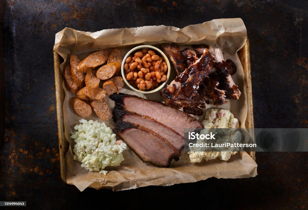 Smoked Meat Plater Dry Rubbed Beef Brisket with Pork Ribs, Chorizo Sausage, Baked Beans, Creamy Coleslaw and Potato Salad Barbecue - Meal Stock Photo