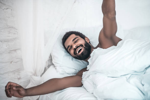 istock Joyful waking man stretching in bed 1314994427