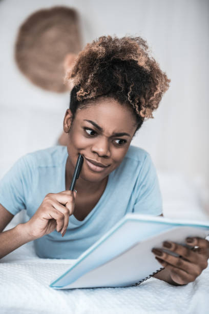 istock Woman with pen lying attentively looking at notepad 1314994495