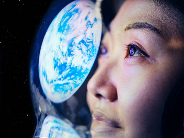 Woman in Space with Earth Reflection A woman wearing a helmet looking at Earth from space. (Earth image provided by NASA) anticipation stock pictures, royalty-free photos & images