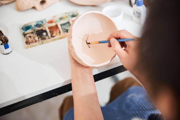 Person painting a tree on bottom on ceramic bowl