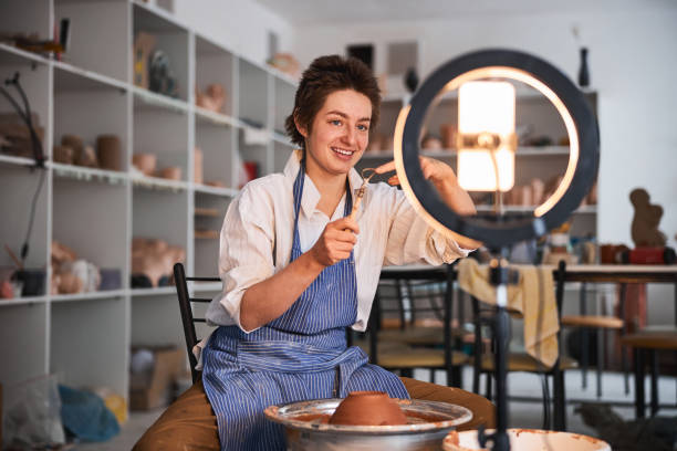istock Potter showing loop tool at mobile phone near pottery wheel 1315003346