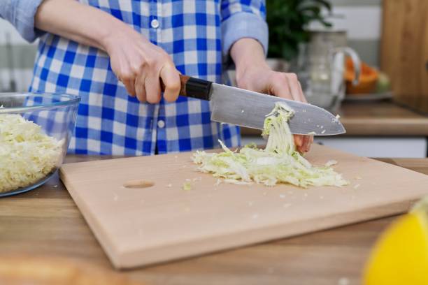 istock Close-up of woman's hand cutting Chinese cabbage on kitchen board 1315004665
