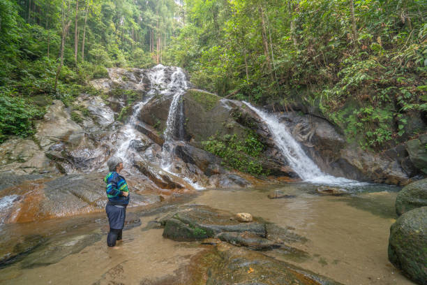 istock Senior woman stands in front of refreshing waterfall 1315009649