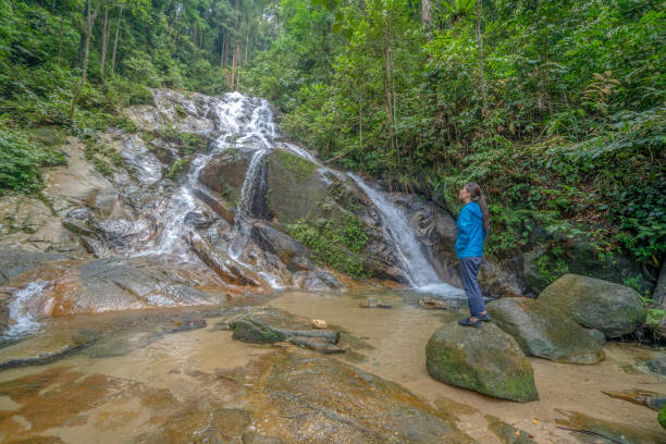 istock Senior woman stands in front of refreshing waterfall 1315009674