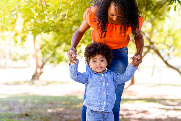 istock Mother helping daughter learn to walk in park 1315010347