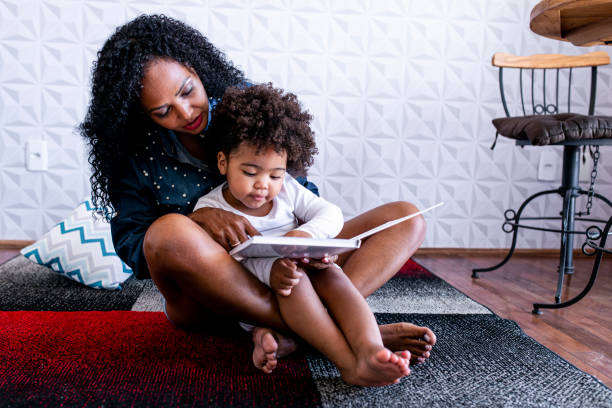 Mother reading children's book to her daughter stock photo