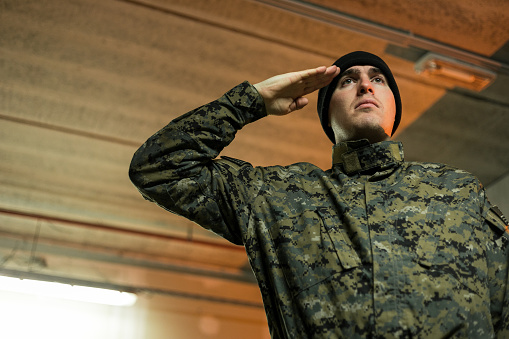Frontview shot of a young soldier standing at a military academy and saluting