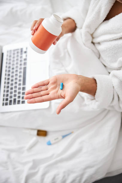 istock Unrecognized female showing medication in arms while sitting in room indoors 1315013058