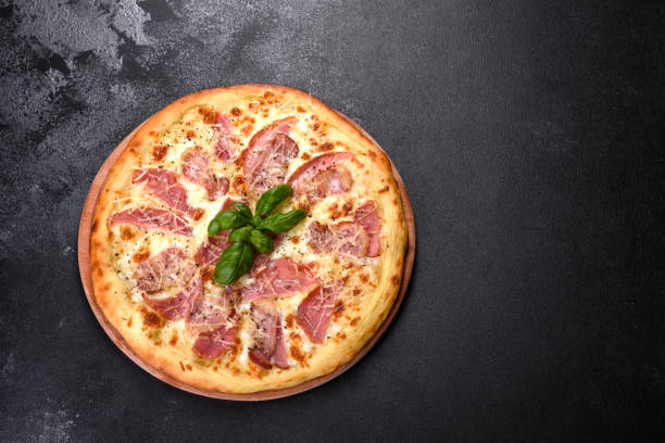 istock Delicious fresh crispy pizza from the oven with ham, cheese and basil 1315015724