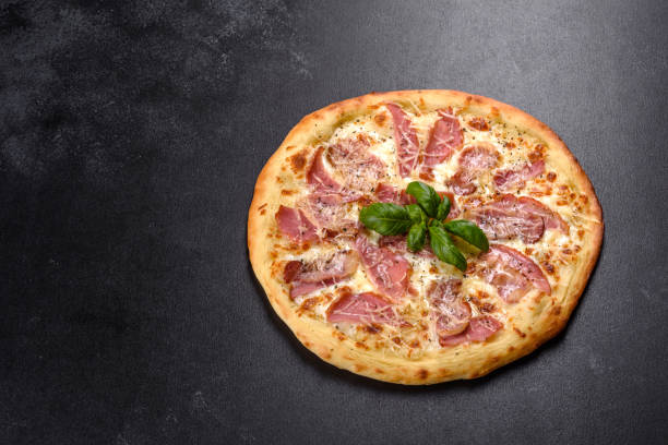 istock Delicious fresh crispy pizza from the oven with ham, cheese and basil 1315015729
