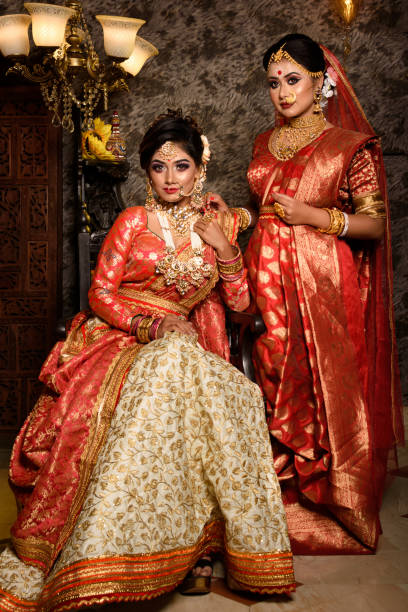 Magnificent young Indian brides in luxurious bridal costume with makeup and heavy jewellery with classic vintage interior in studio lighting. Wedding Lifestyle and Fashion stock photo