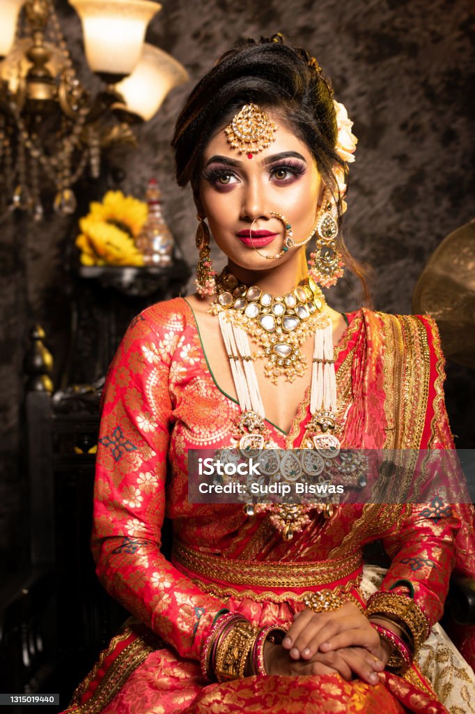 Stunning Indian Bride In Luxurious Bridal Costume With Makeup And Heavy  Jewellery Is Sitting In A Chair In With Classic Vintage Interior In Studio  Lighting Wedding Lifestyle And Fashion Stock Photo -