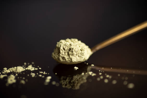 Matcha tea powder on a spoon on dark background