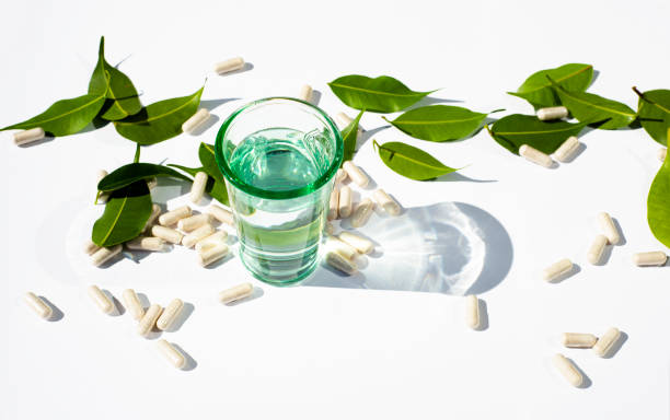 흰색 배경에 물과 캡슐과 알약 유리 컵. 녹색 잎 건강 기능 과 보충의 주제. 텍스트에 대한 대체 의학 복사 공간. - chinese medicine nutritional supplement herb pill 뉴스 사진 이미지