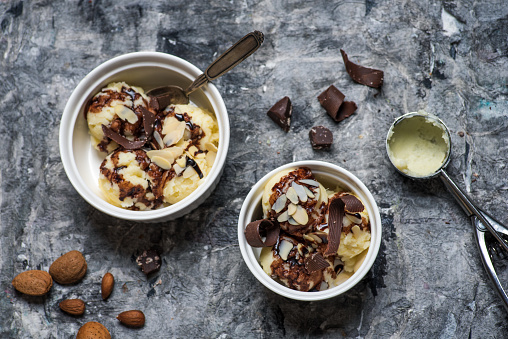 Homemade vanilla ice cream with almonds and hazelnuts in a cup on a rustic table top view