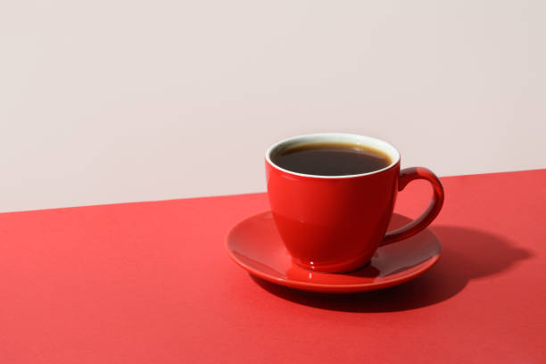 Red cup of coffee and beans on red.