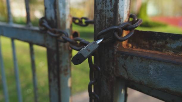 istock Closed Metal Gate Secured with Iron Chain and Simple Padlock 1315032690