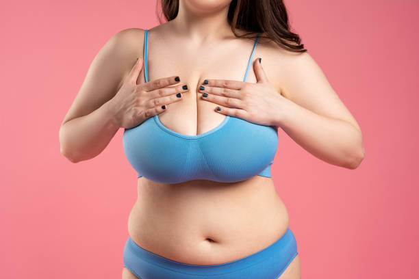 Woman checking her very large breasts for cancer on pink background Woman checking her very large breasts for cancer on pink background, health care concept drooping photos stock pictures, royalty-free photos & images