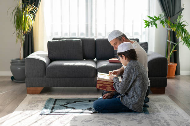 Son and father reading Koran together at home Son and father reading Koran together at home allah stock pictures, royalty-free photos & images