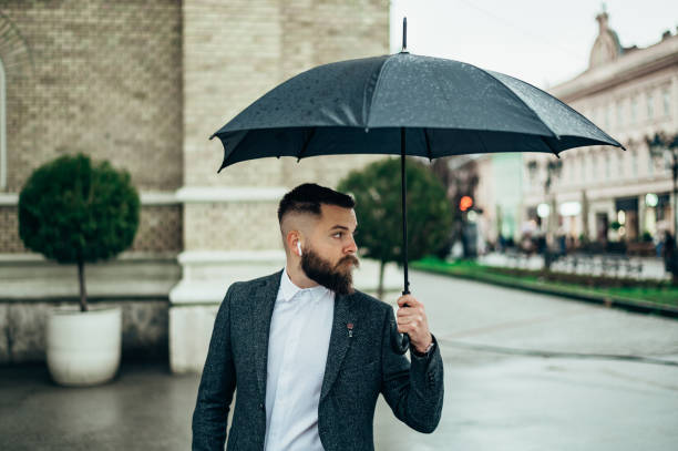 istock Young businessman using an airpods and holding a black umbrella 1315042123